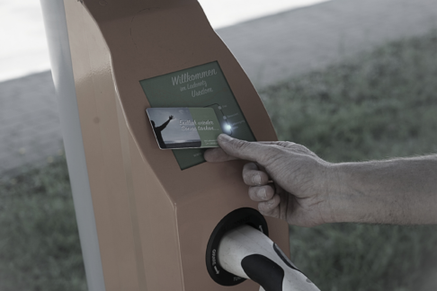 Hand holding a charge card at an Inselwerke AC charge point.
